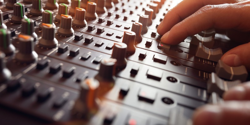 Person adjusting sound recording studio mixer